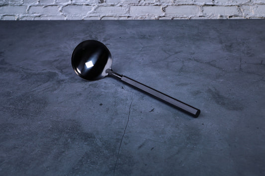 Stainless steel oxidized ladle — full view showing blackened solid bowl, ferrule, and wooden handle