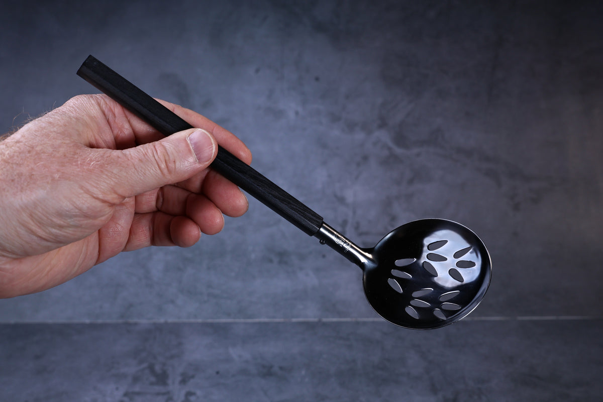 Stainless steel oxidized perforated ladle — octagonal wooden handle and perforated bowl held in hand