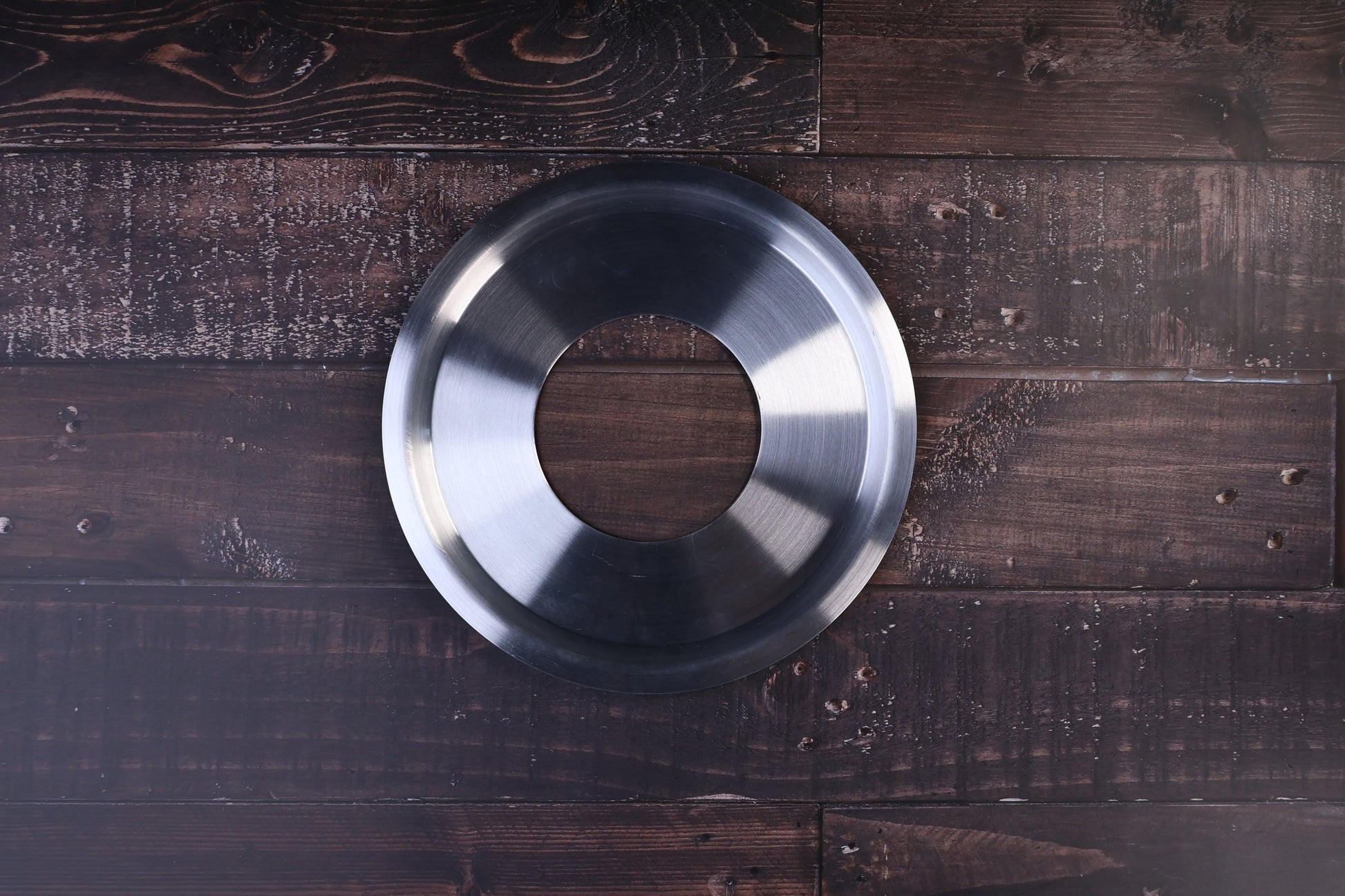 Stainless steel steam ring 21cm shown from above with its open center on a dark wood surface