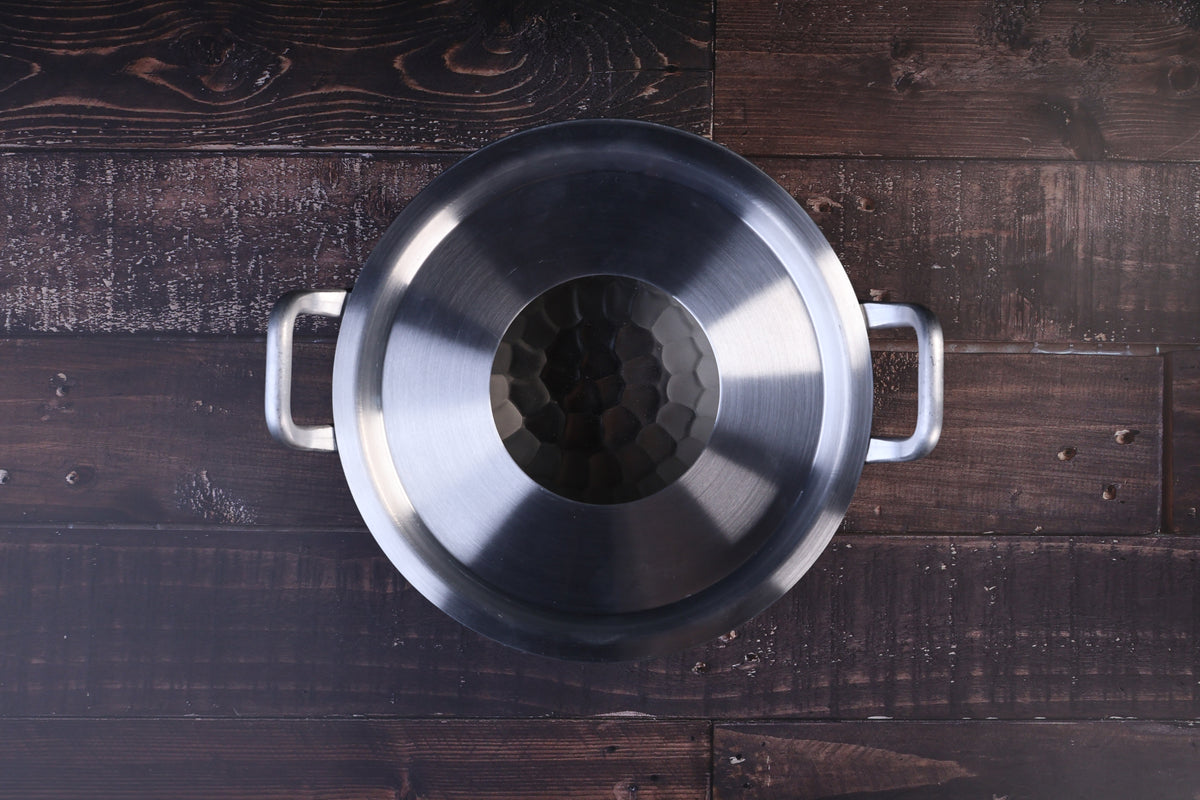 Steam ring 21cm seated inside a stainless pot with handles, viewed from above on a dark wood surface