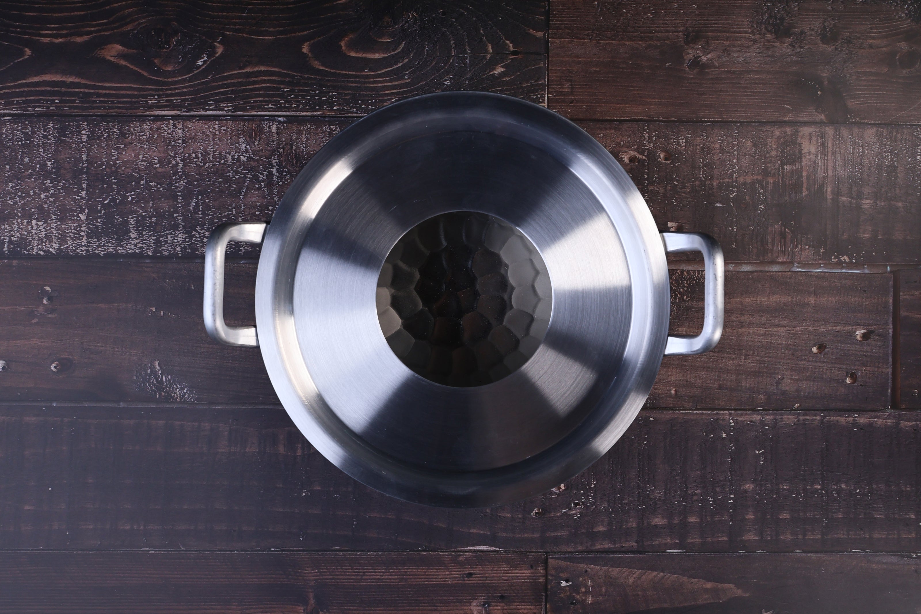 Steam ring 21cm seated inside a stainless pot with handles, viewed from above on a dark wood surface