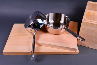 top down image of two japanese saucepans one leaning on the other on top of wood cutting boards in grey background