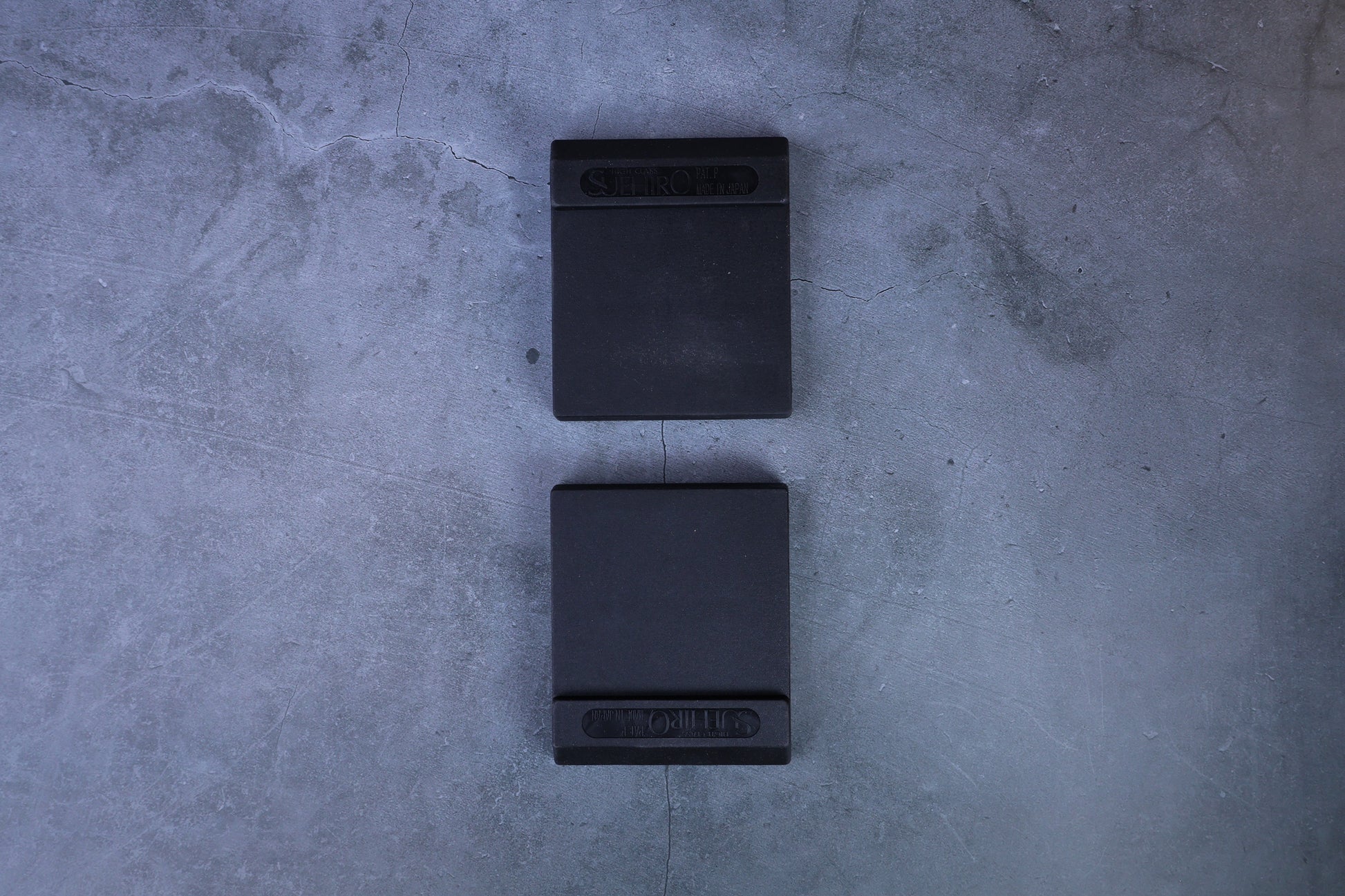 Two Suehiro rubber whetstone bases arranged vertically, straight overhead view showing both from above
