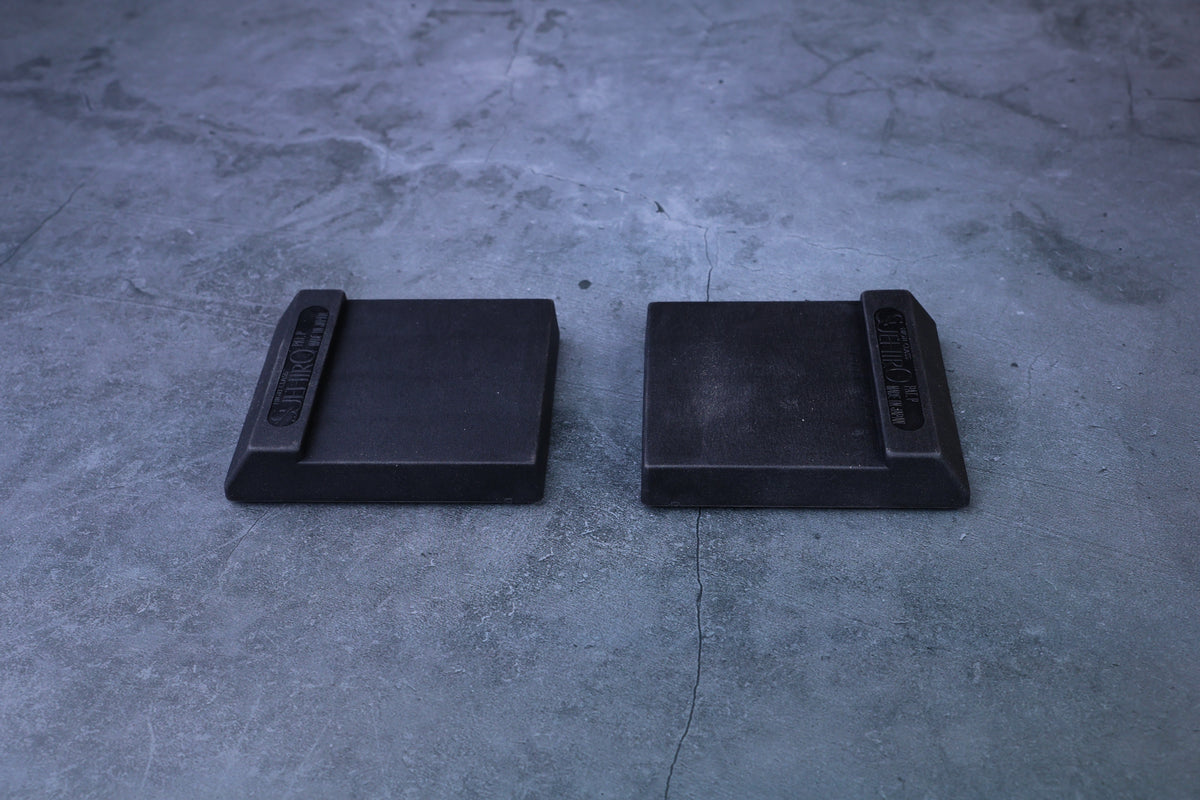 Two Suehiro rubber whetstone bases displayed side by side, overhead view showing flat surface and branded end tabs