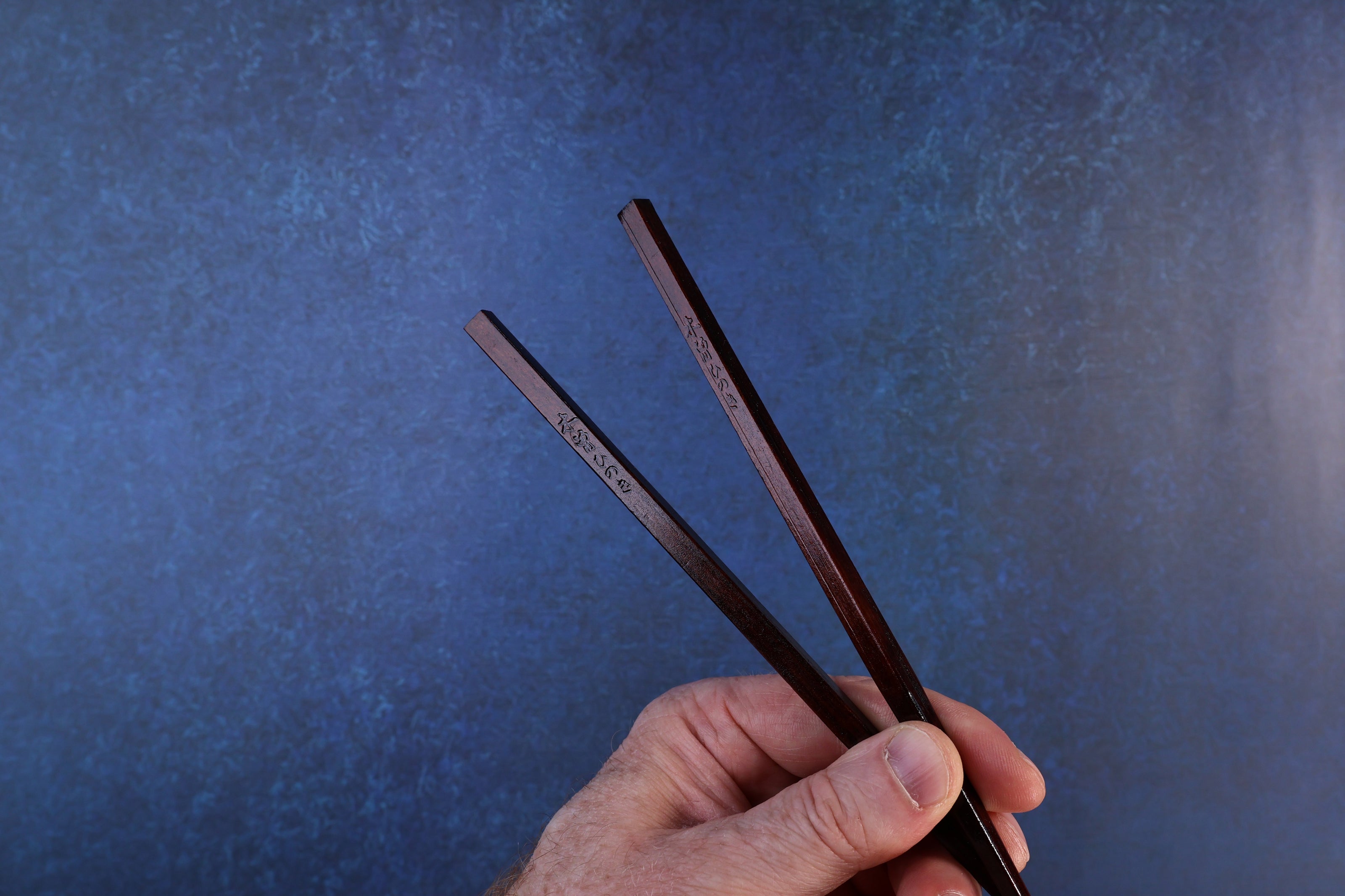 Suri Urushi Hinoki chopsticks 22cm angled view on hinoki board showing deep red urushi lacquer and handle end