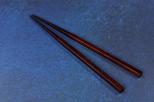 Suri Urushi Hinoki chopsticks 22cm laid flat on blue surface showing full length and Japanese engraving