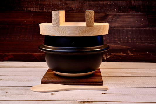 Suzuki Co. Hagama Rice Cooker 3 Cup wooden lid on dark wood trivet with rice paddle
