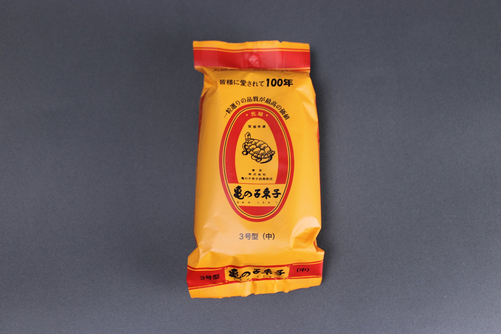 top down image of kamenoko tawashi brush in plastic yellow and red package with grey background 