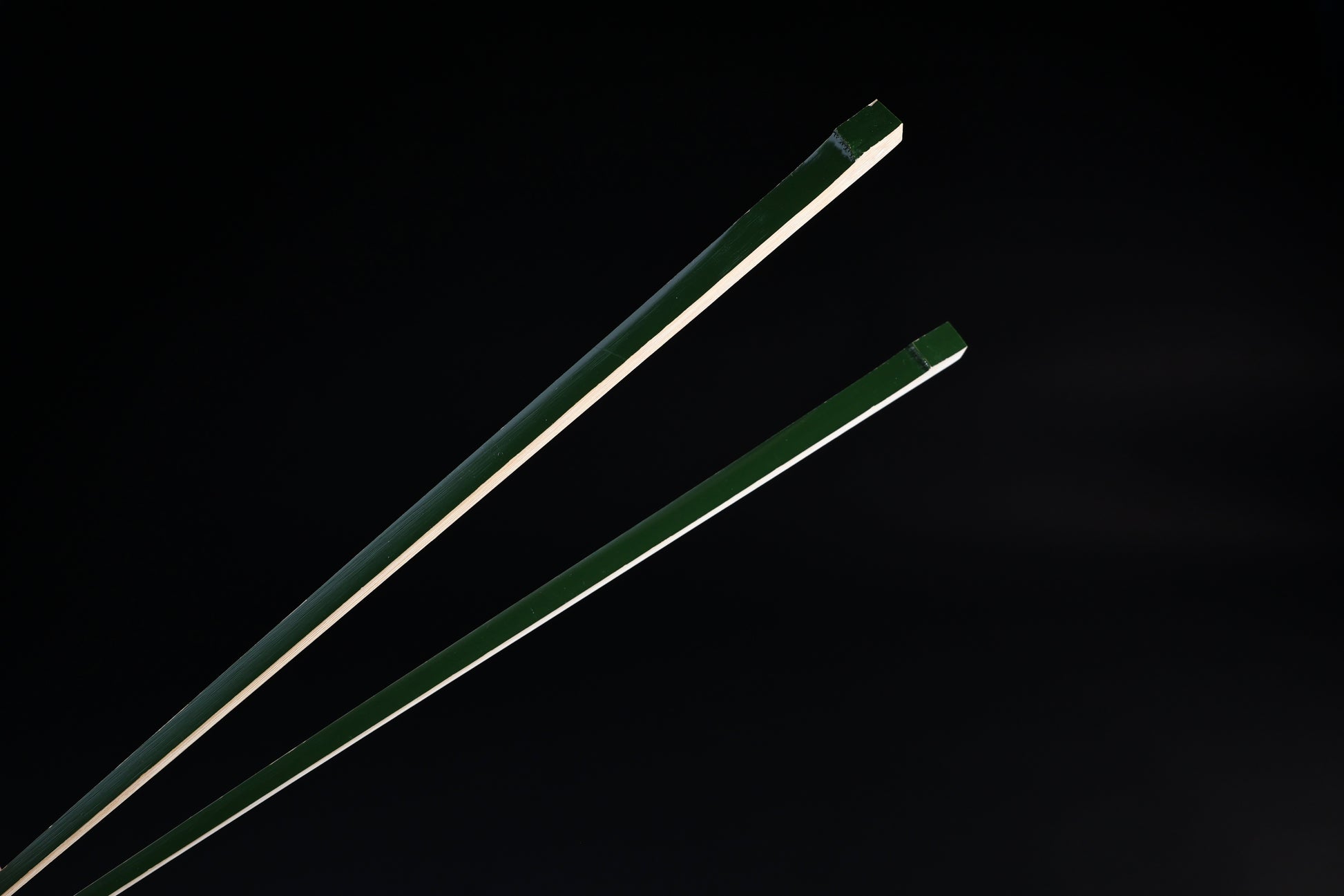 Tenbushi dark green bamboo chopsticks top ends close against black, showing square green lacquered grip ends