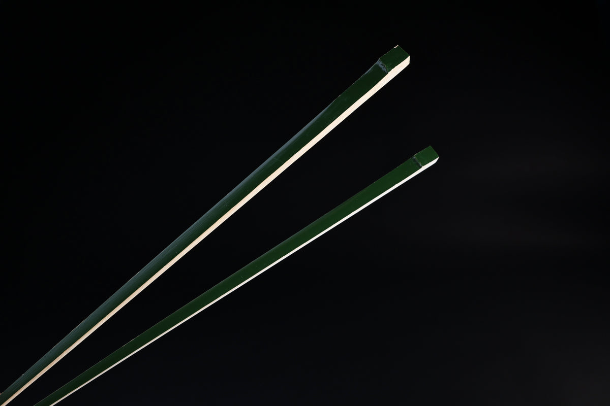 Tenbushi dark green bamboo chopsticks top ends close against black, showing square green lacquered grip ends