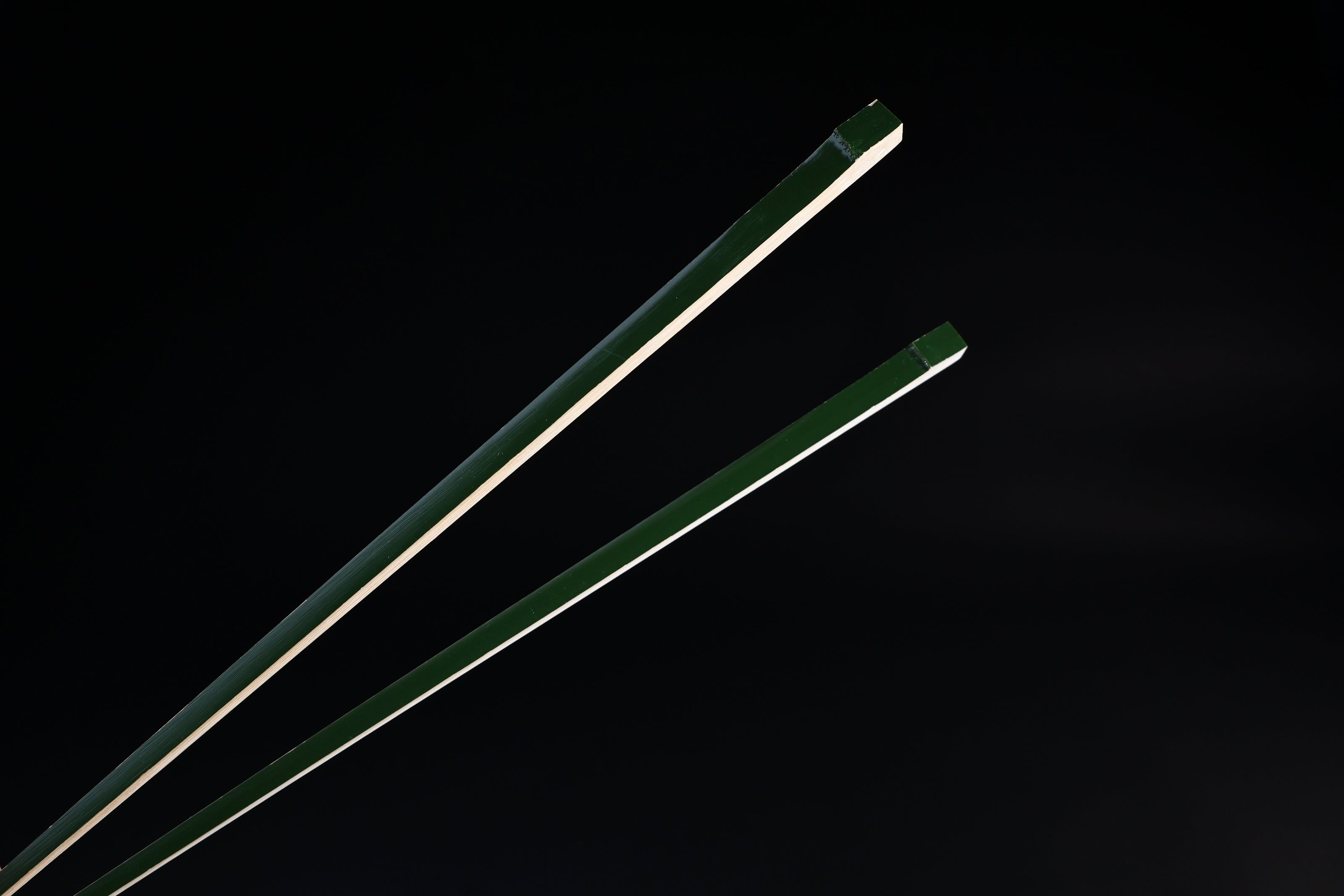 Tenbushi dark green bamboo chopsticks top ends close against black, showing square green lacquered grip ends