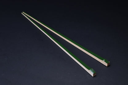 Tenbushi dark green bamboo chopsticks angled on black, square lacquered ends and tapered natural bamboo tips visible