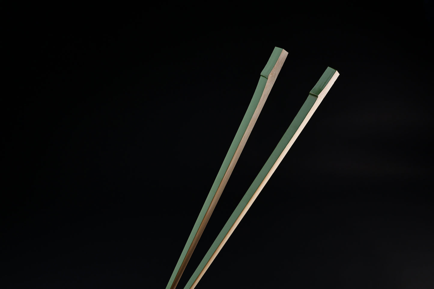 Tenbushi light green bamboo chopsticks top ends close against black, showing square green lacquered grip ends