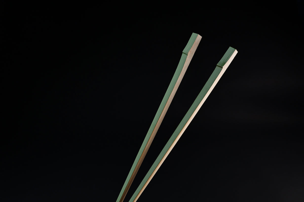 Tenbushi light green bamboo chopsticks top ends close against black, showing square green lacquered grip ends