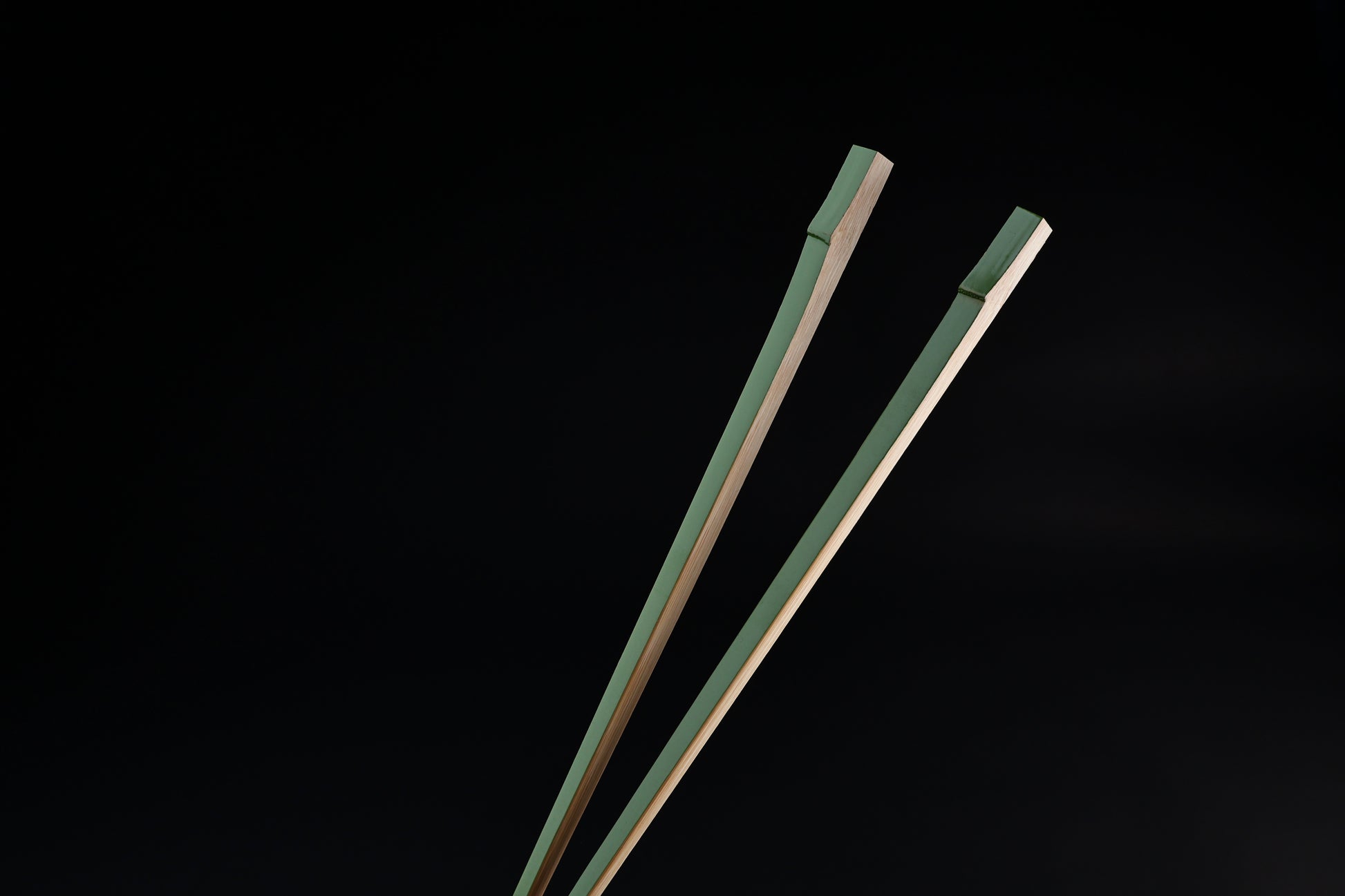 Tenbushi light green bamboo chopsticks top ends close against black, showing square green lacquered grip ends