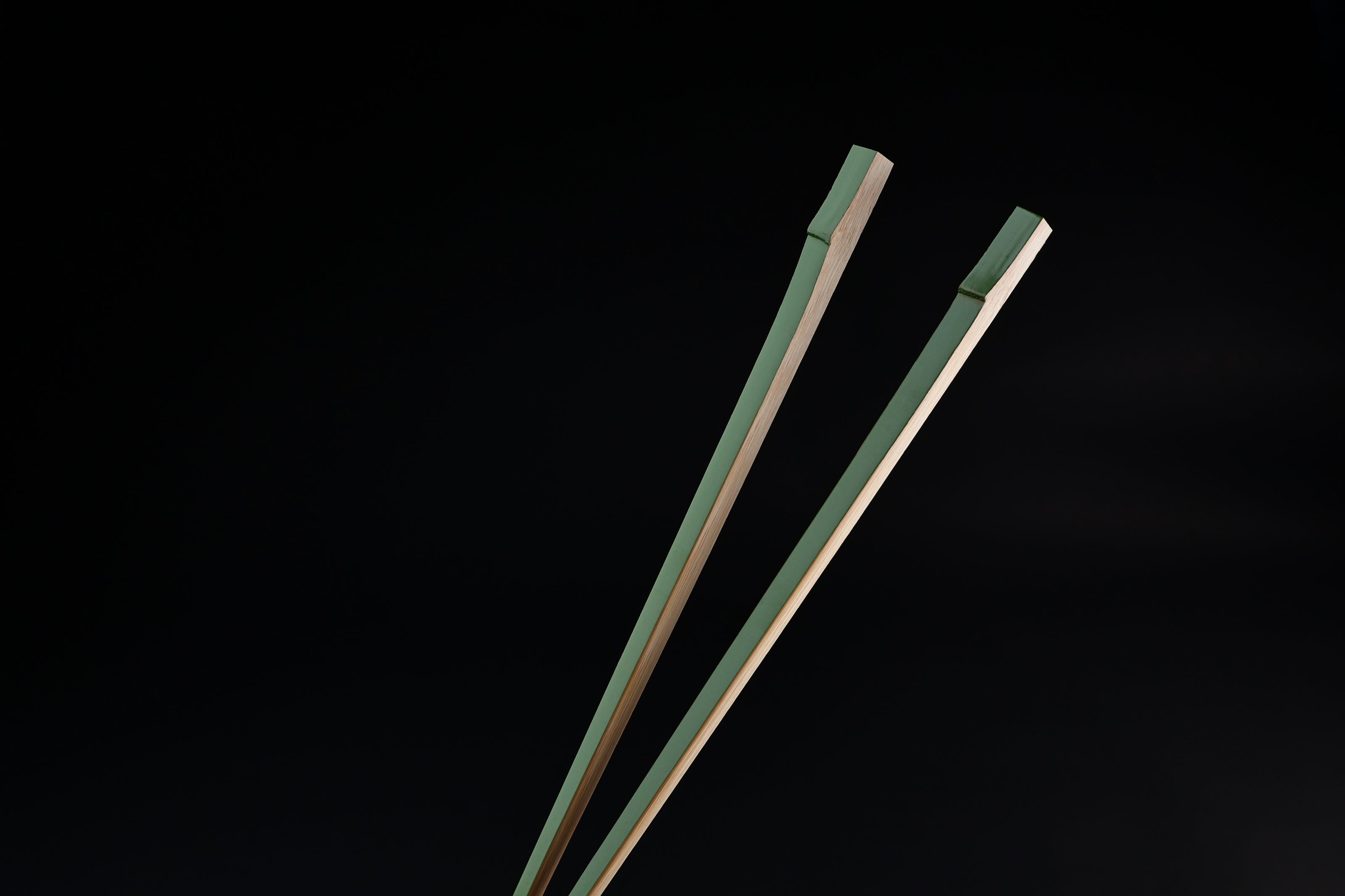 Tenbushi light green bamboo chopsticks top ends close against black, showing square green lacquered grip ends