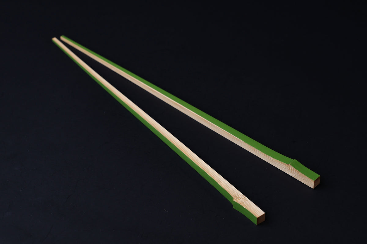 Tenbushi light green bamboo chopsticks angled on black, square lacquered ends and tapered natural bamboo tips visible