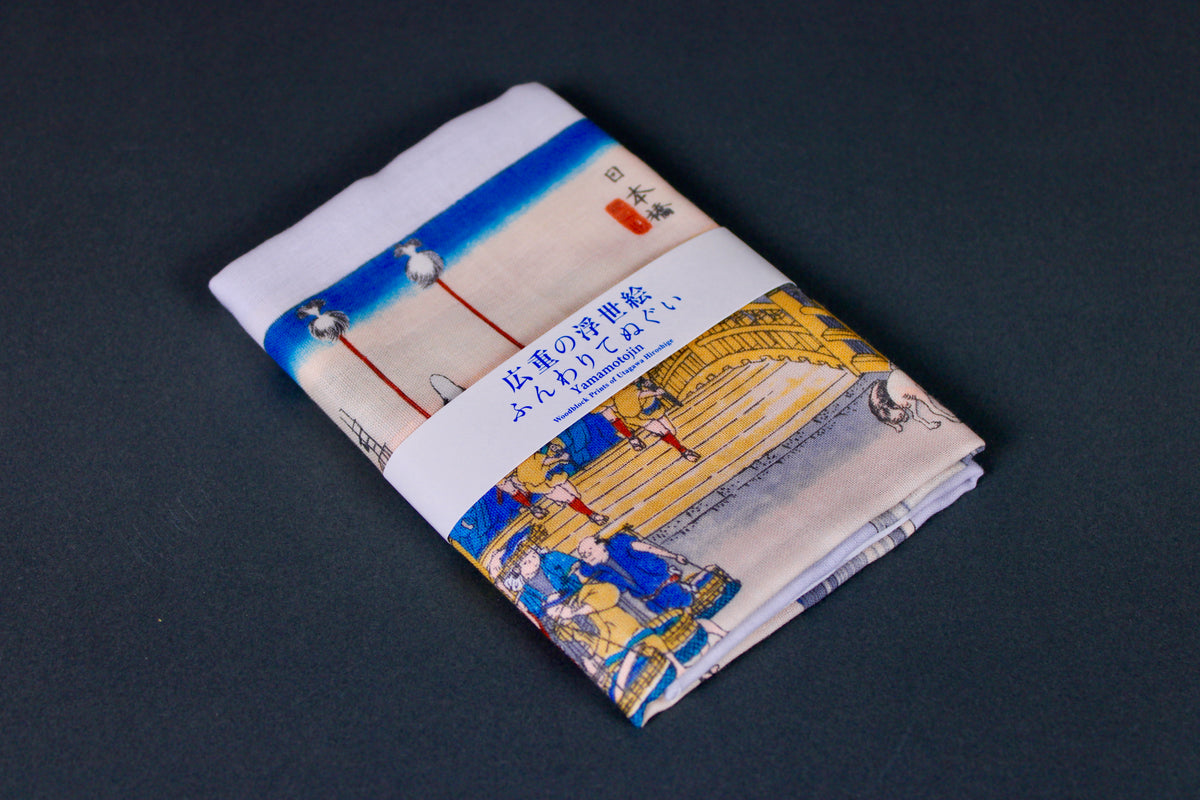 rectangular packaged tenugui towel printed with deep blue red grey classical japanese bridge on dark backdrop