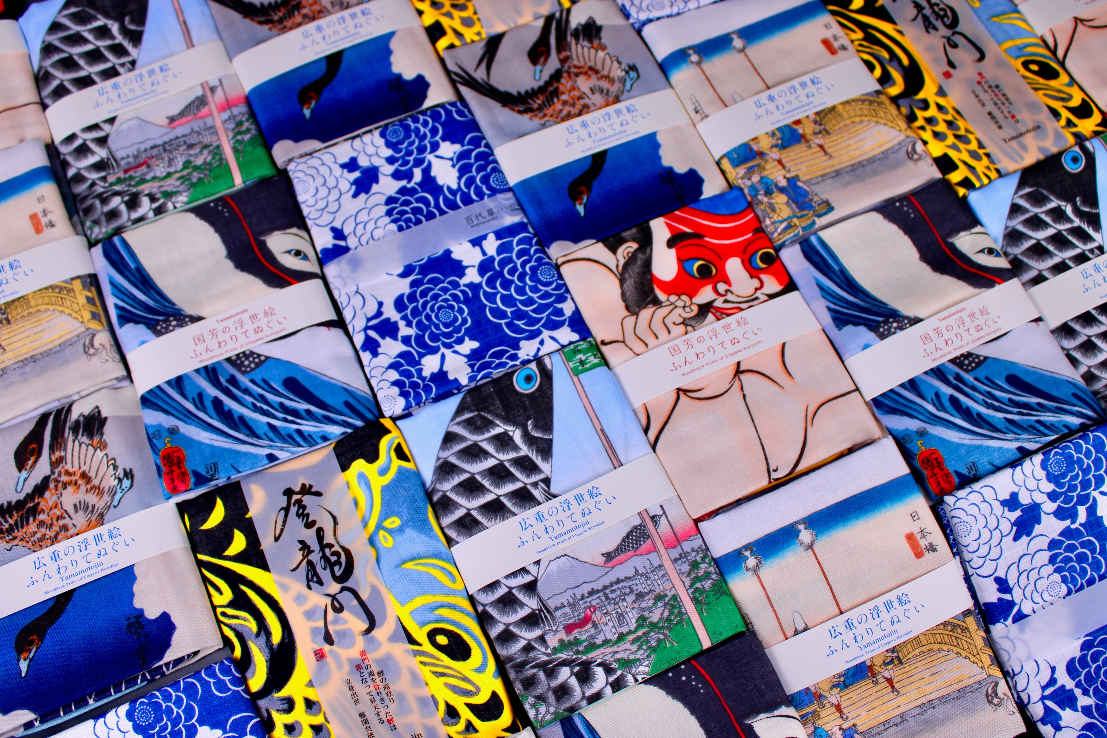 multiple brightly colored tenugui towels colored blue yellow red pink each towel neatly wrapped 
