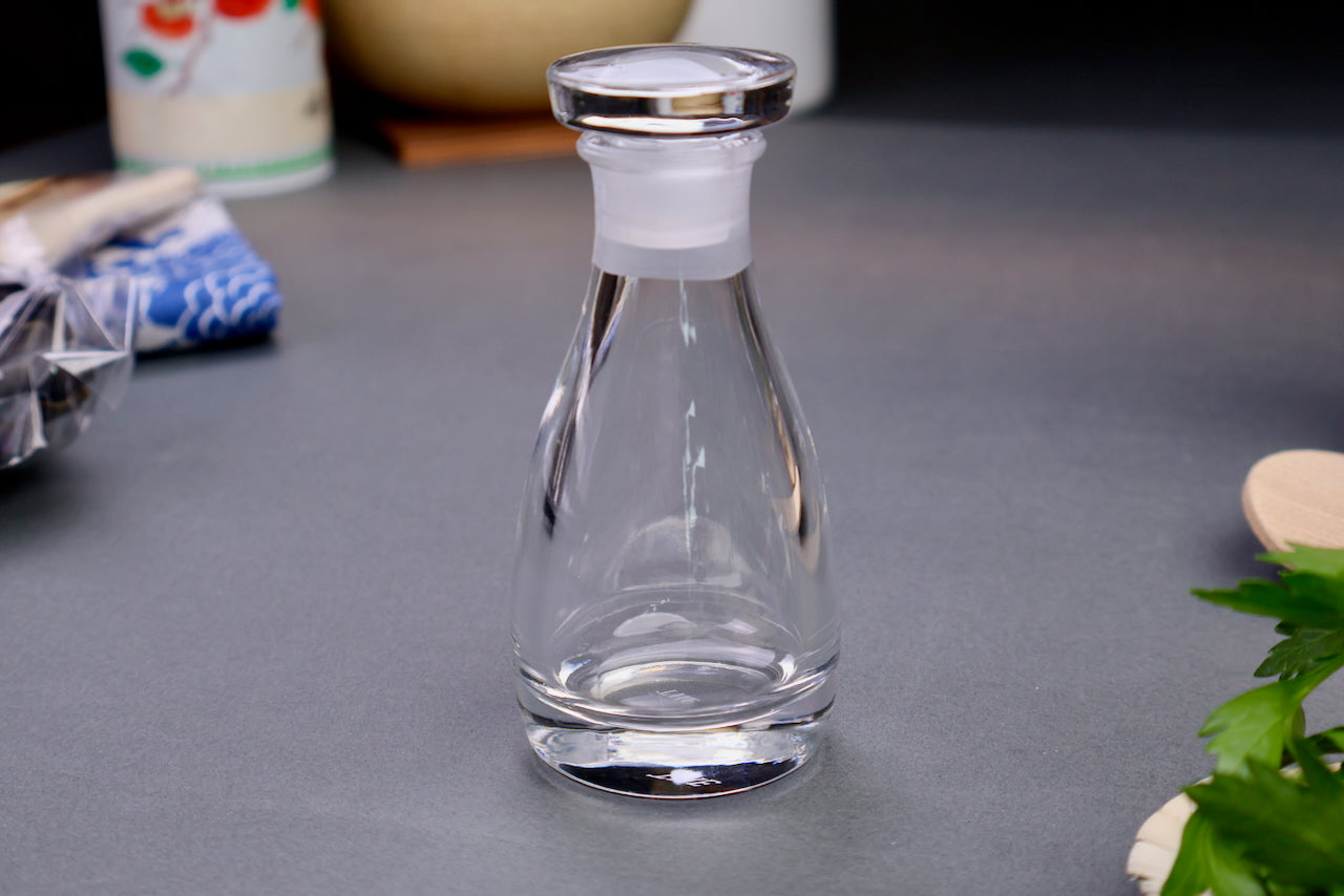 THE soy sauce cruet made in Japan elegant crystal glass product smooth circular lid elongated body printed name on bottom surrounding kitchenware gray background