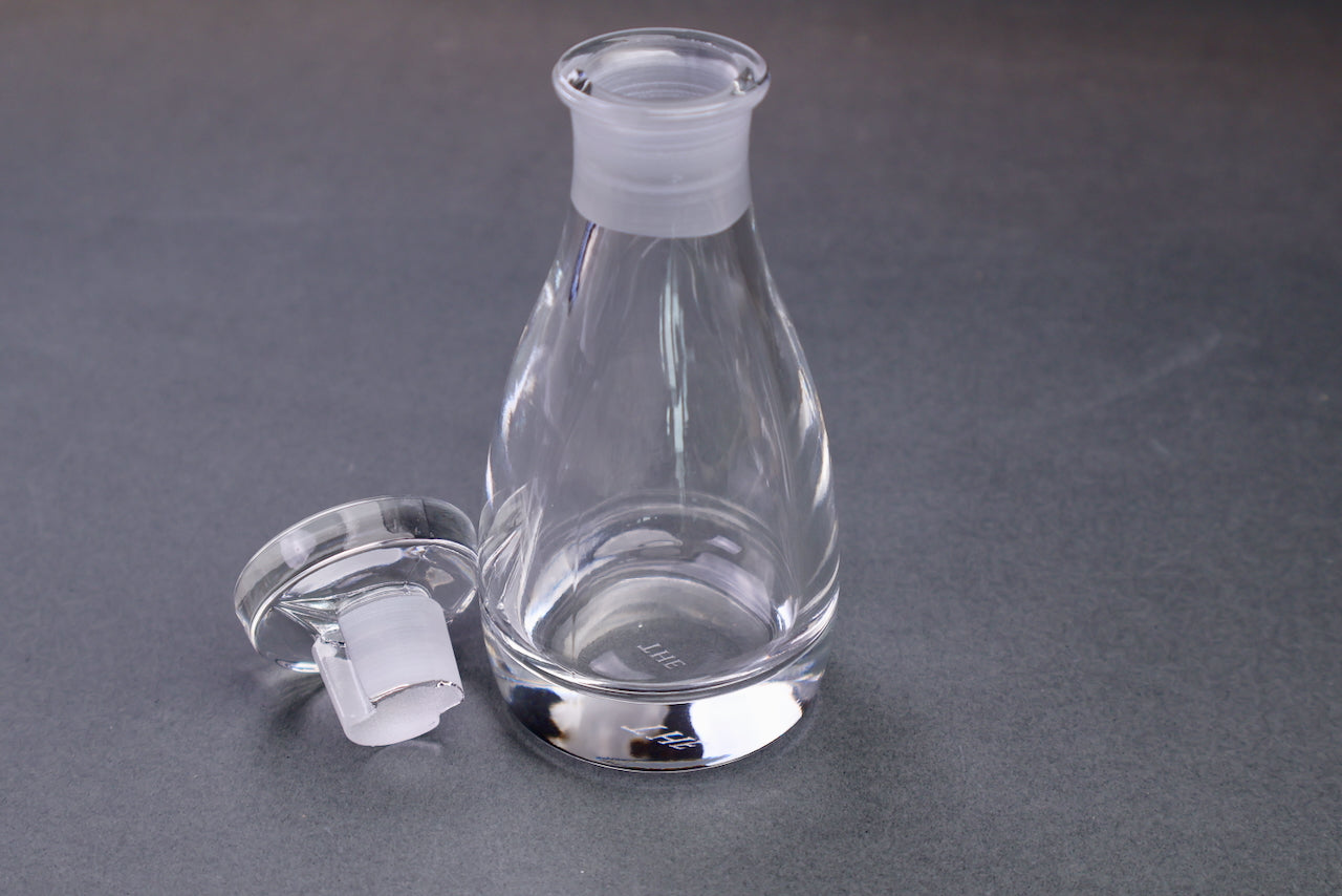 japanese kitchenware crystal glass cruet elongated body circular lid beside dark grey background with package and container