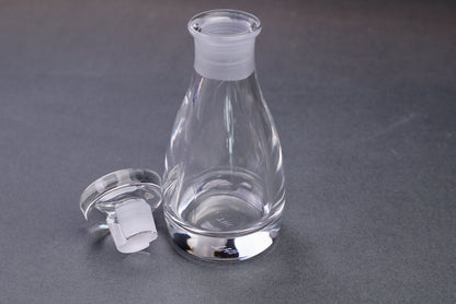 japanese kitchenware crystal glass cruet elongated body circular lid beside dark grey background with package and container