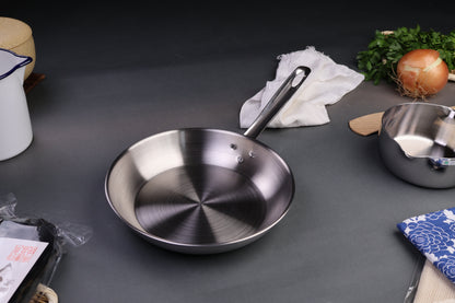 three layer aluminum clad stainless steel saute pan with long curved handled silver tone centered around japanese kitchenware dark grey backdrop