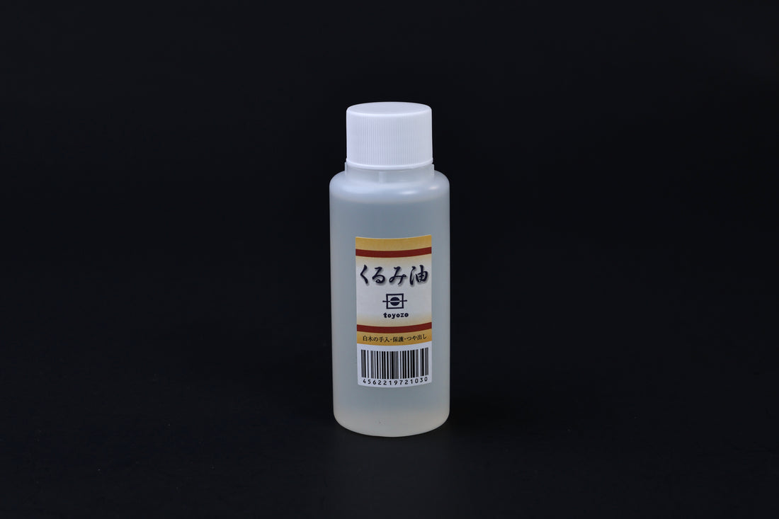 Toyozo kurumi walnut oil bottle held in hand showing size and Japanese label on black background