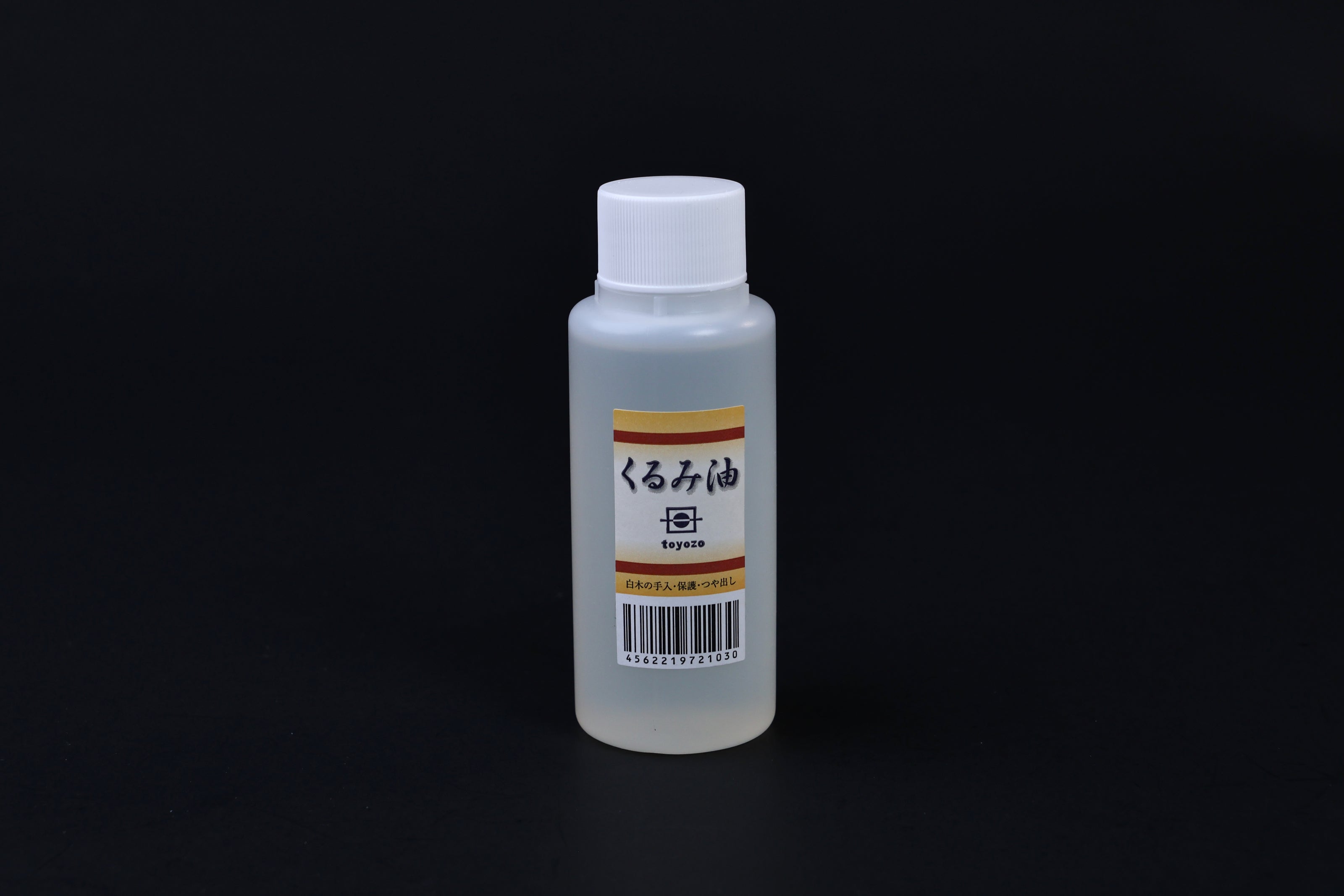 Toyozo kurumi walnut oil bottle held in hand showing size and Japanese label on black background