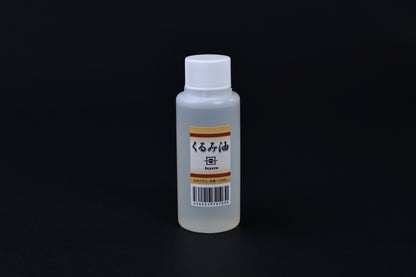 Toyozo kurumi walnut oil bottle held in hand showing size and Japanese label on black background