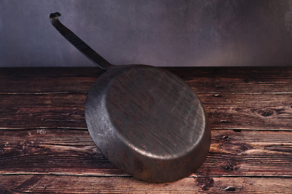 Underside of the Turk hand-forged iron frying pan showing the hammered base and forged handle