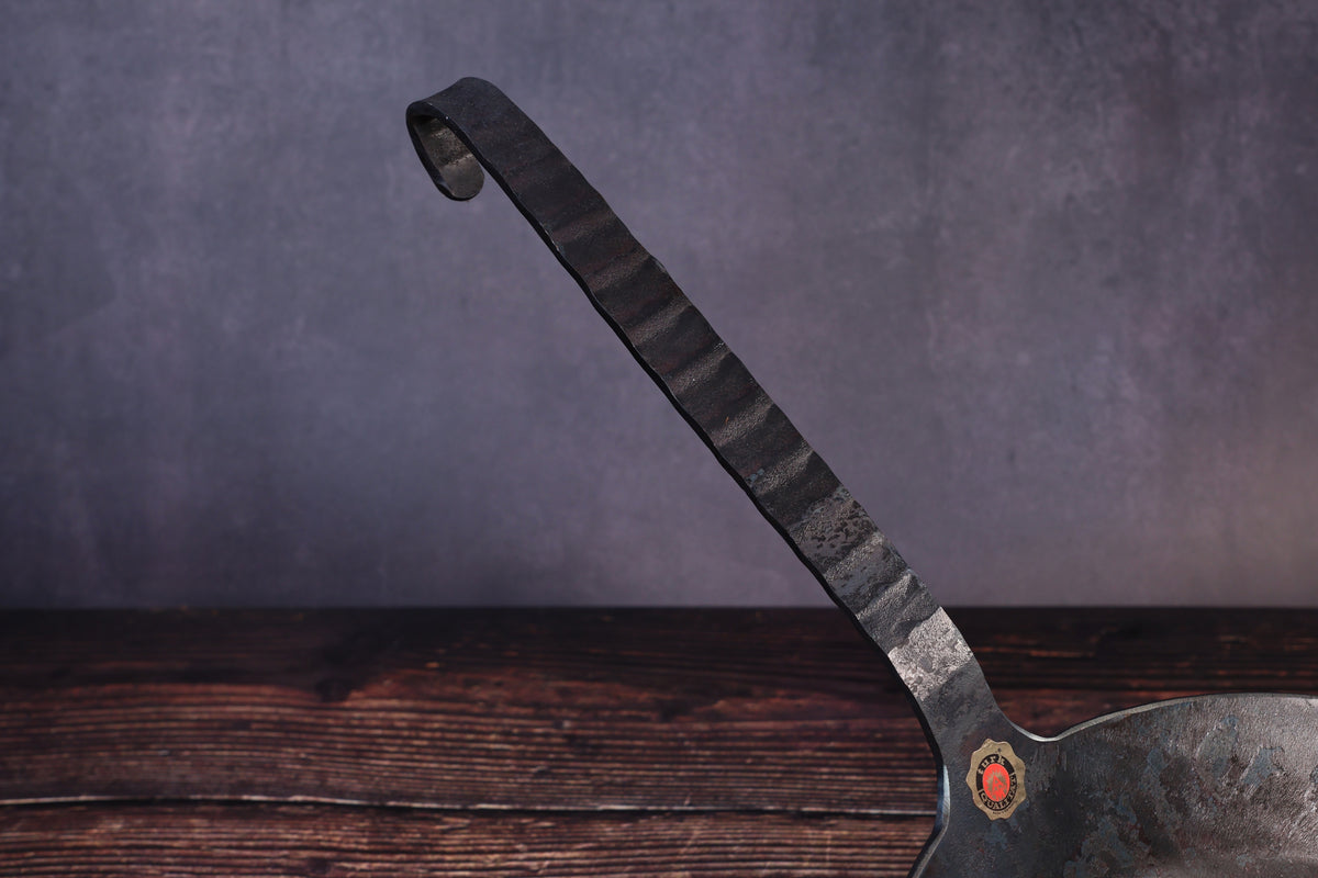 Close detail of the Turk pan's faceted forged iron handle and looped hanging end