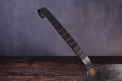 Close detail of the Turk pan's faceted forged iron handle and looped hanging end