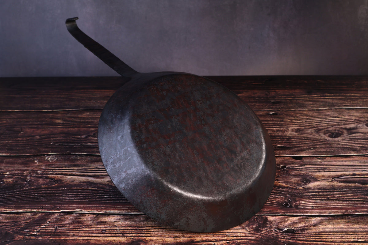 Underside of the Turk hand-forged iron frying pan showing the hammered base and forged handle