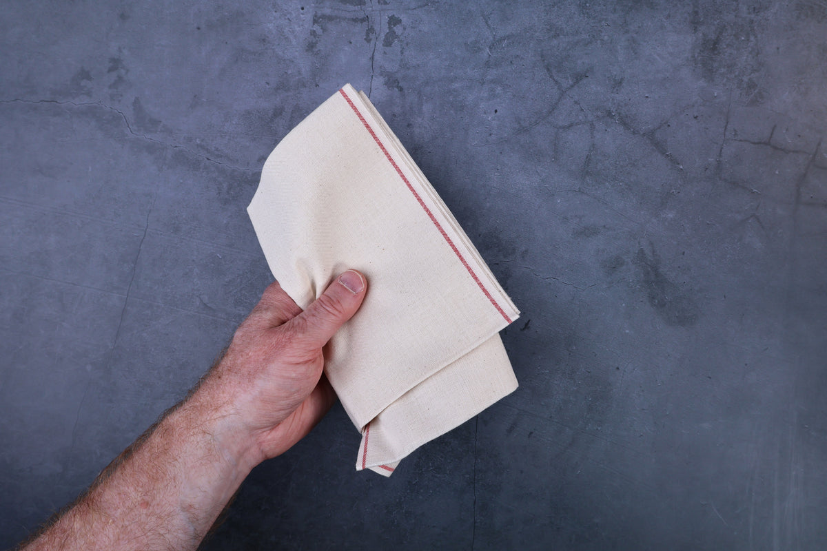 Unbleached cotton cloth pack of 3 — hand holding folded cloths showing weight and thickness