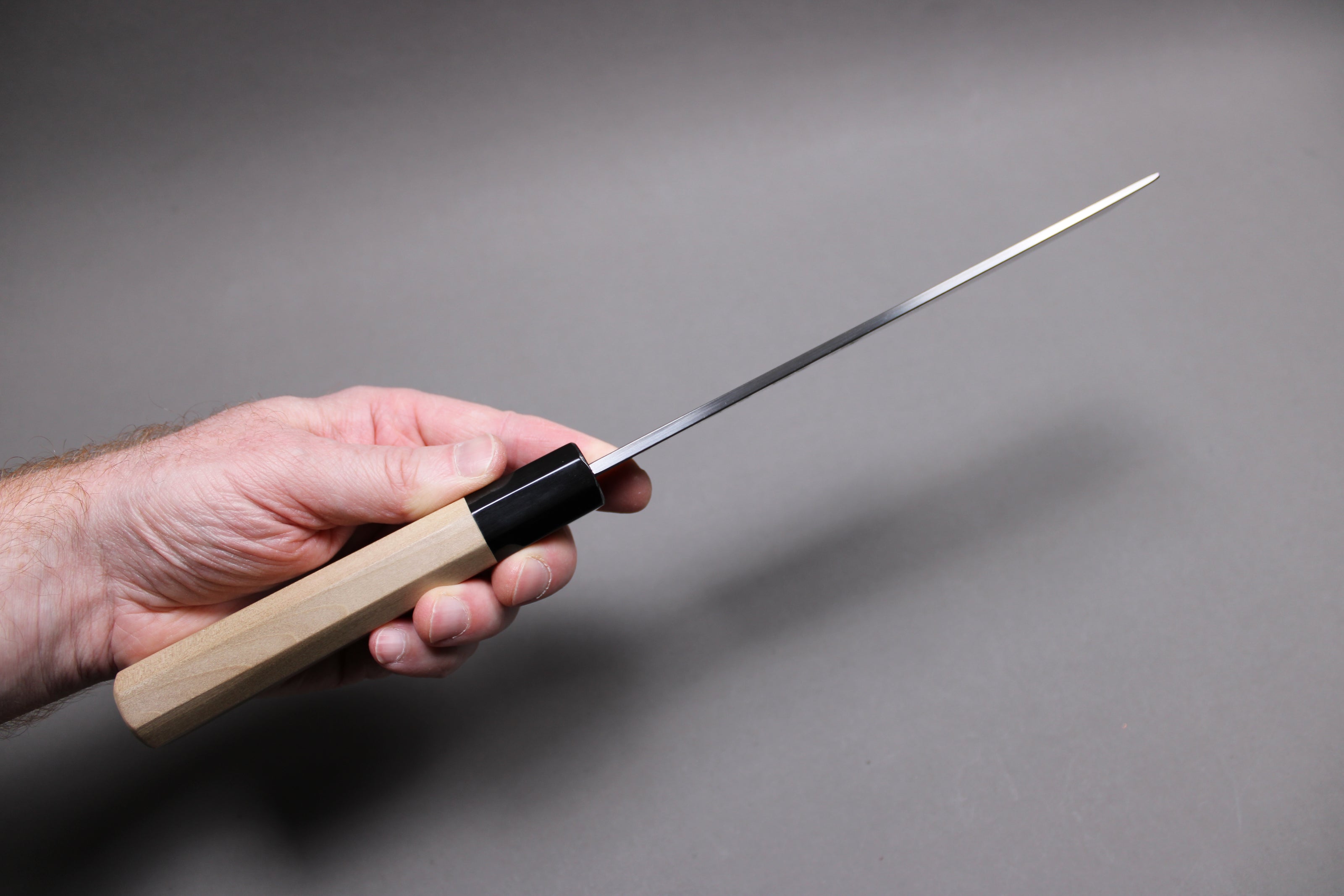  hand holding usuba knife showing spine of knife and distal tapering