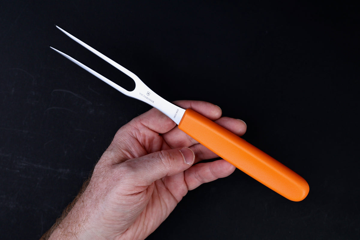 Victorinox Swiss Classic carving fork — full profile showing tine spread, bolster, and orange handle in hand