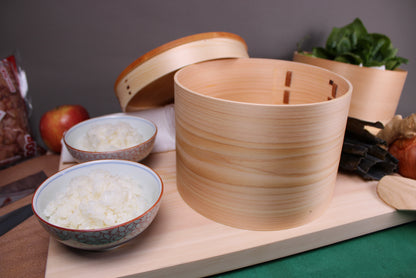 kiso hinoki round rice container lid leaning beside 2 japanese bowls of prepared rice atop hinoki cutting board