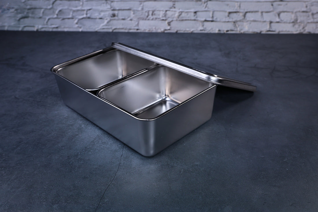 Yakumi 2-compartment condiment pan with lid propped open, stainless steel compartments visible inside