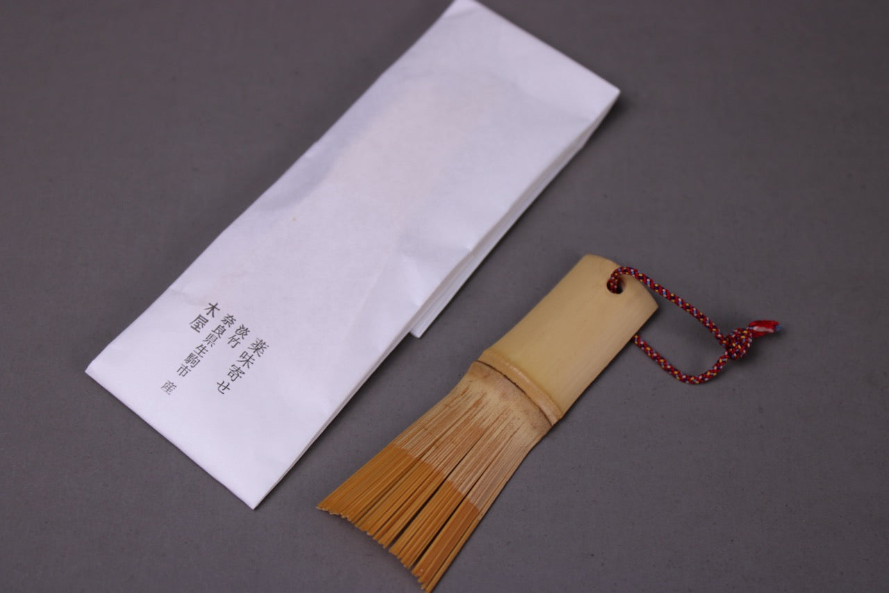 yakumiyose bamboo brush by kiya for oroshigane and suribachi scraping beside paper wrapping displaying brand name and product 