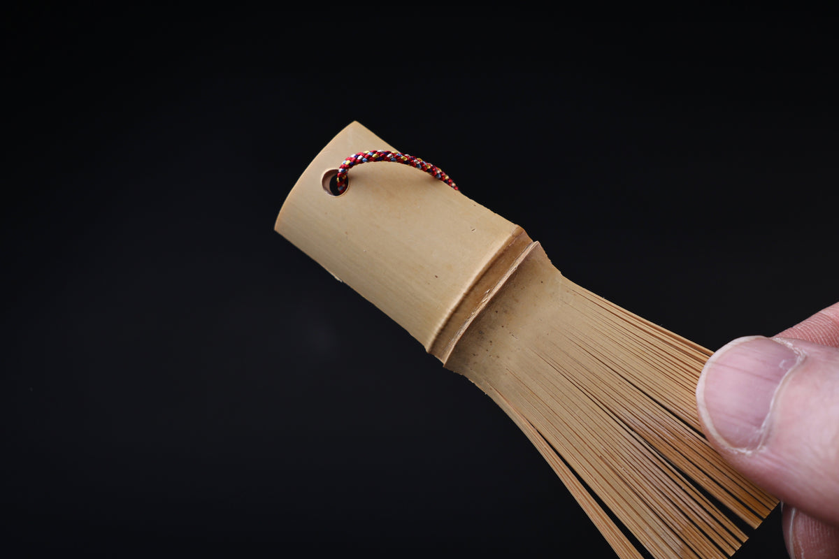 Close view of the Yakumiyose bamboo brush handle, cord loop, and the base of the split bamboo bristles