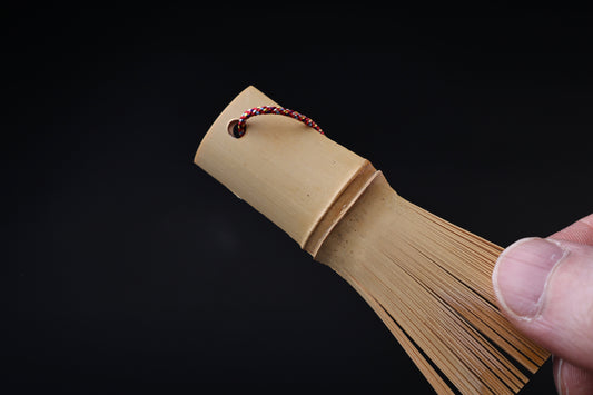 Close view of the Yakumiyose bamboo brush handle, cord loop, and the base of the split bamboo bristles