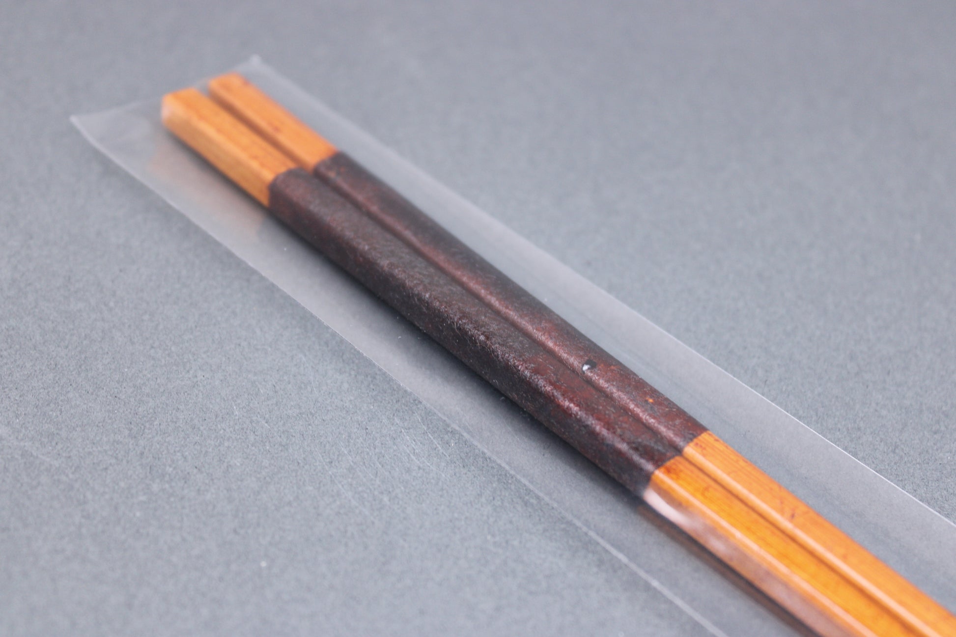 long square brownish tan bamboo cooking chopsticks urushi lacquered in clear packaging white product paper description in hiragana grey backdop