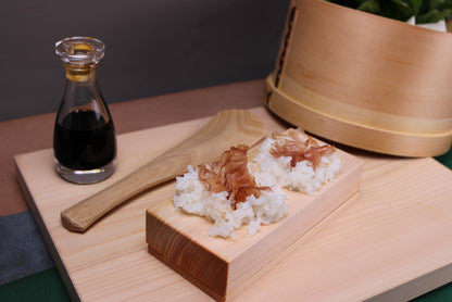 kisou life youbi onigiri rice ball maker filled with rice katsuobushi atop cutting board beside soy sauce cruet with kitchen background 