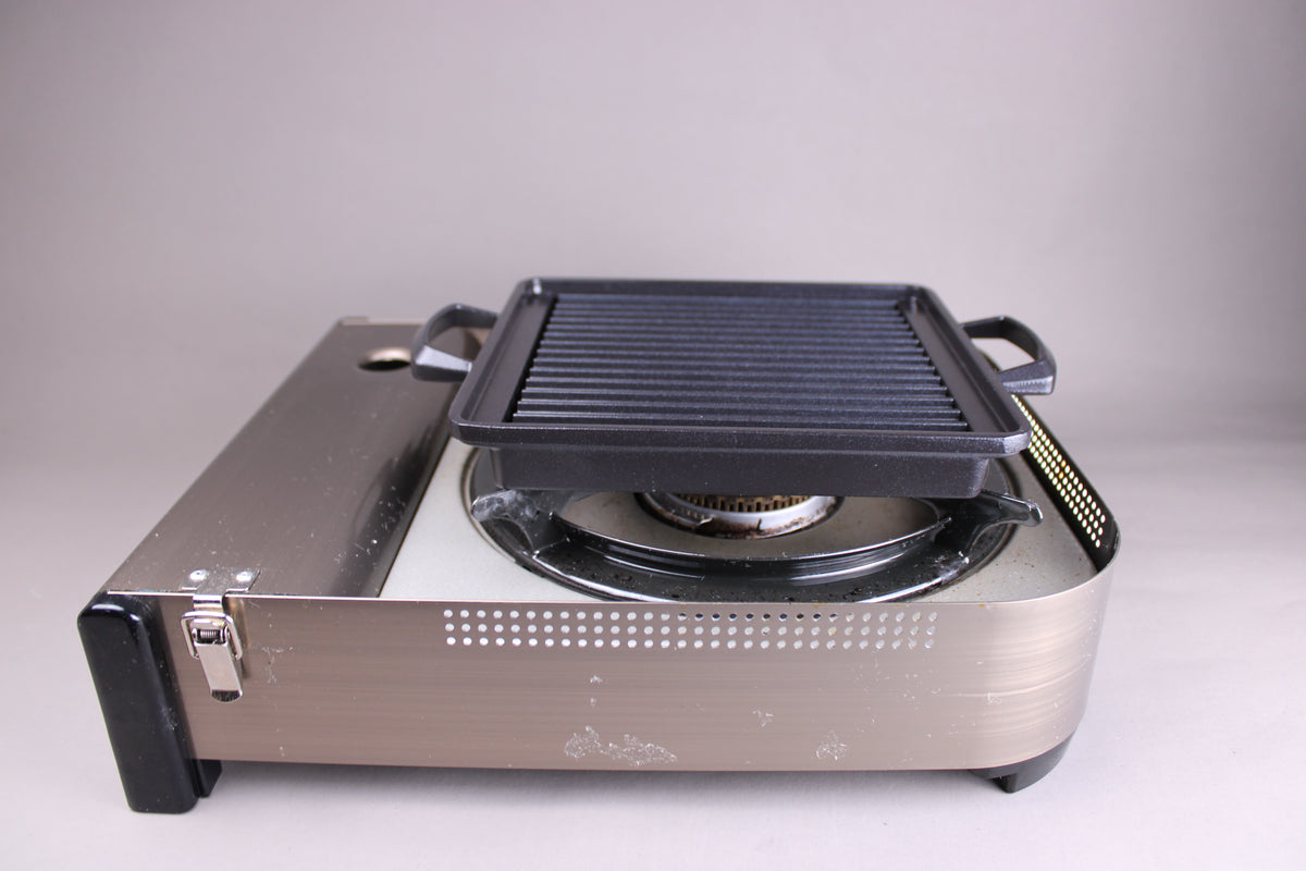Yamacoh square grill — seated on portable gas stove, side view showing ridged cooking surface in use context