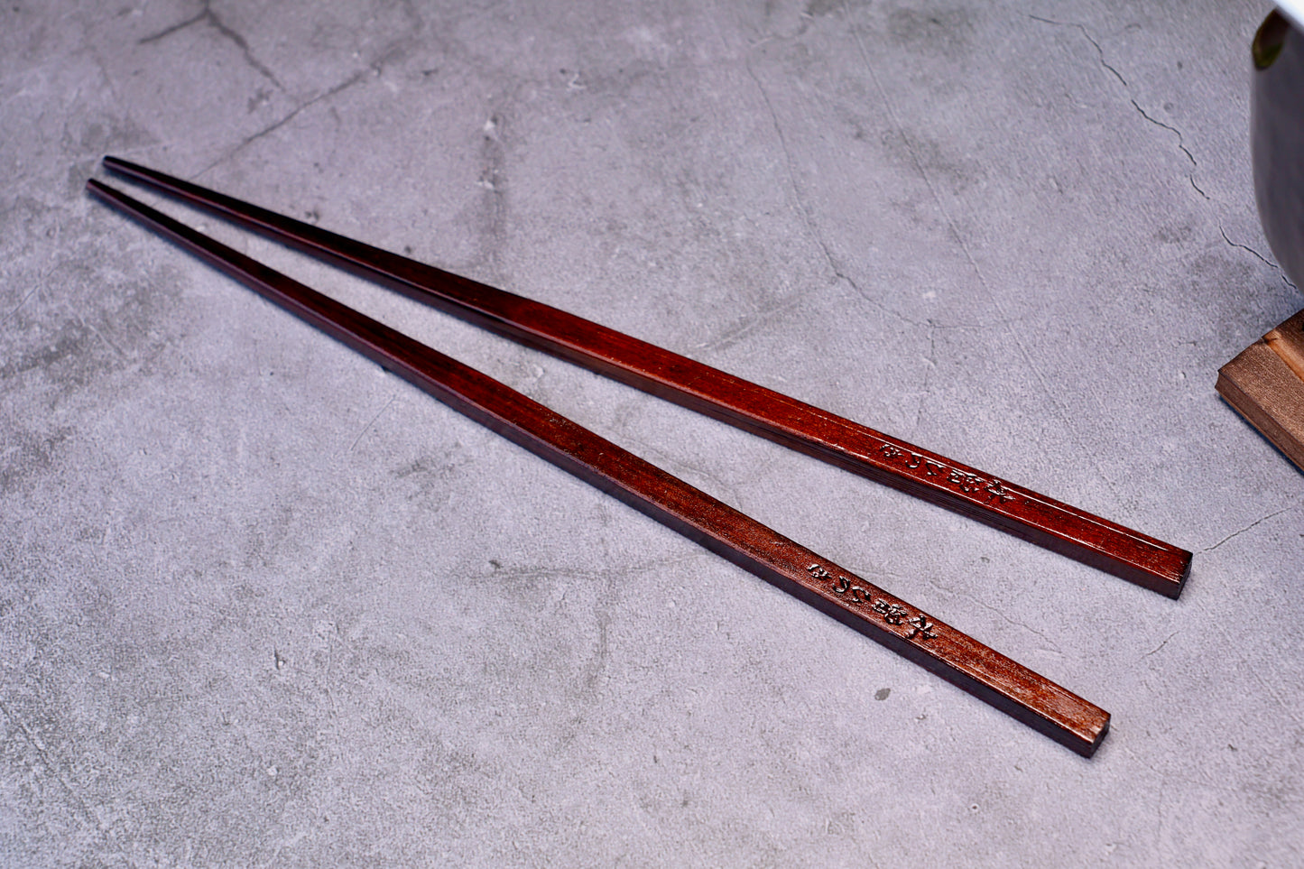 Yamacoh Suri Urushi Chopsticks Hinoki 22cm, pair showing deep urushi lacquer finish on concrete surface