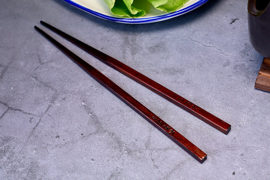 Yamacoh Suri Urushi Chopsticks Hinoki 22cm, pair on concrete with blue-rimmed plate of greens in background