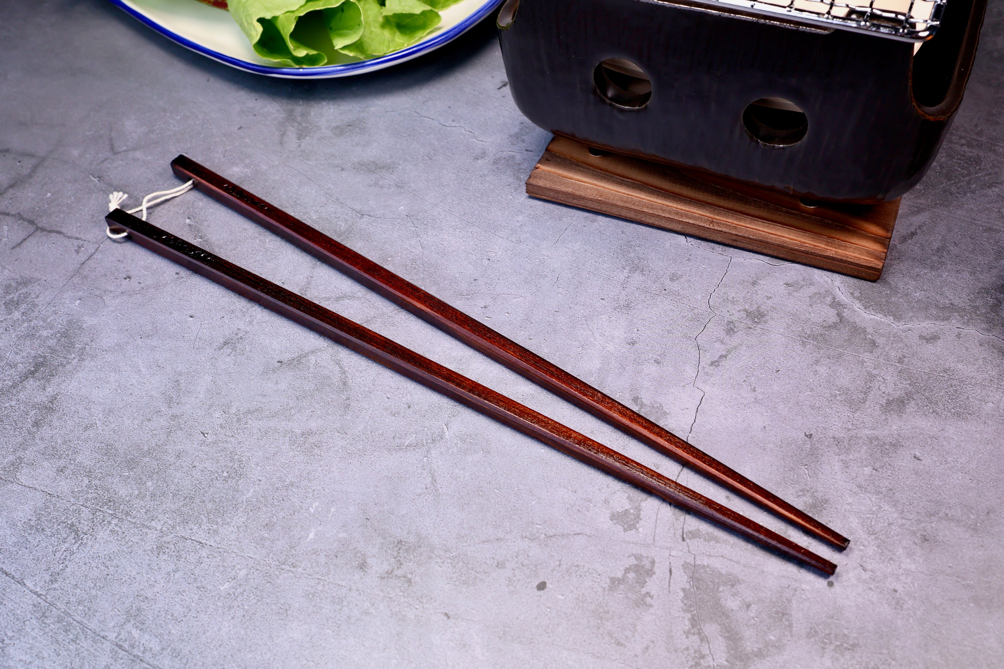 Yamacoh Suri Urushi Cooking Chopsticks Hinoki 33cm, pair at wider spread on concrete showing full length and lacquer surface