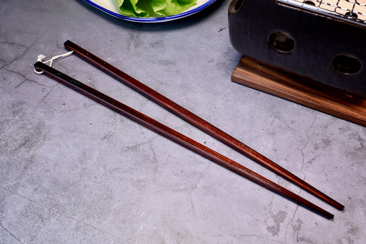 Yamacoh Suri Urushi Cooking Chopsticks Hinoki 33cm, full length pair on concrete showing urushi lacquer finish and cotton twine