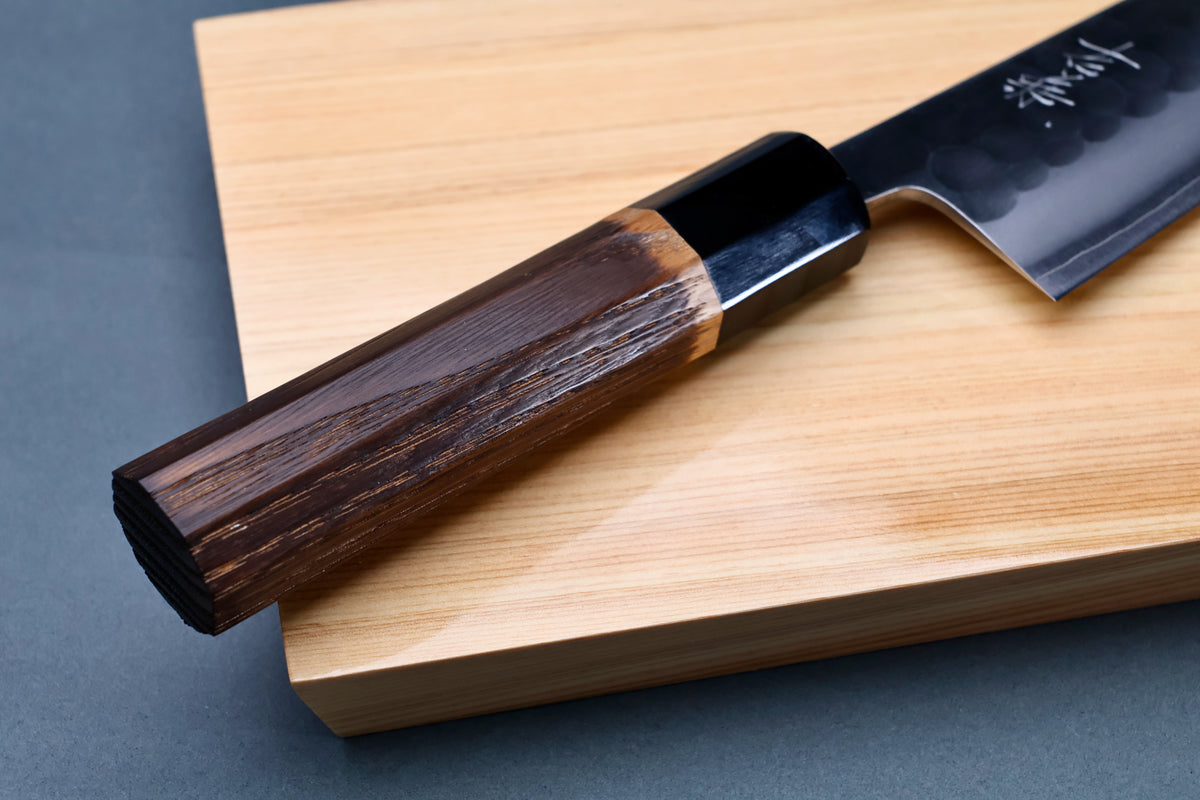 Yoshikane SKD Tsuchime Gyuto 210mm close-up of burnt chestnut octagonal handle and buffalo horn collar on hinoki board